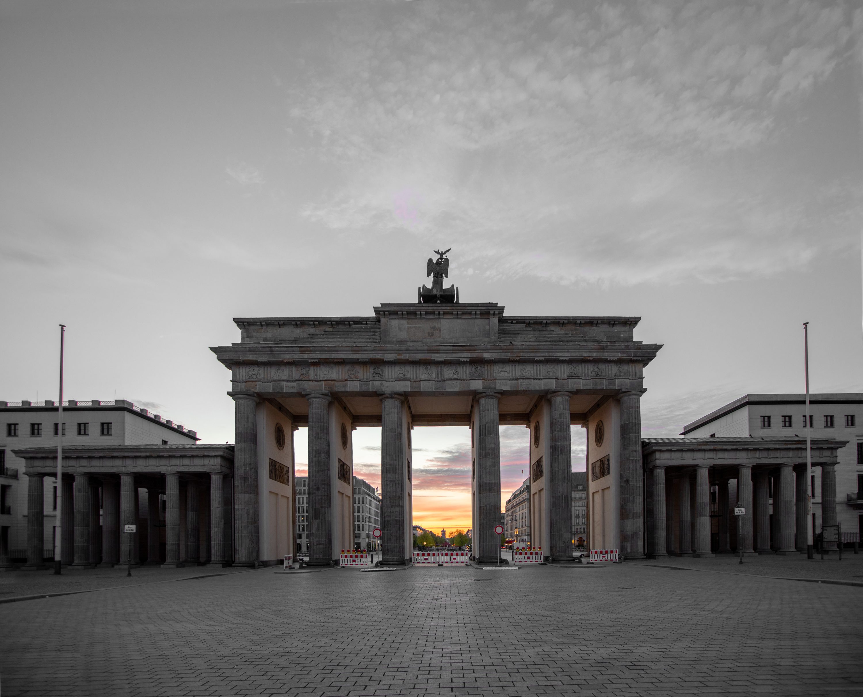 The Brandenburg Gate framing the soft golden sunrise of an early Berlin morning.