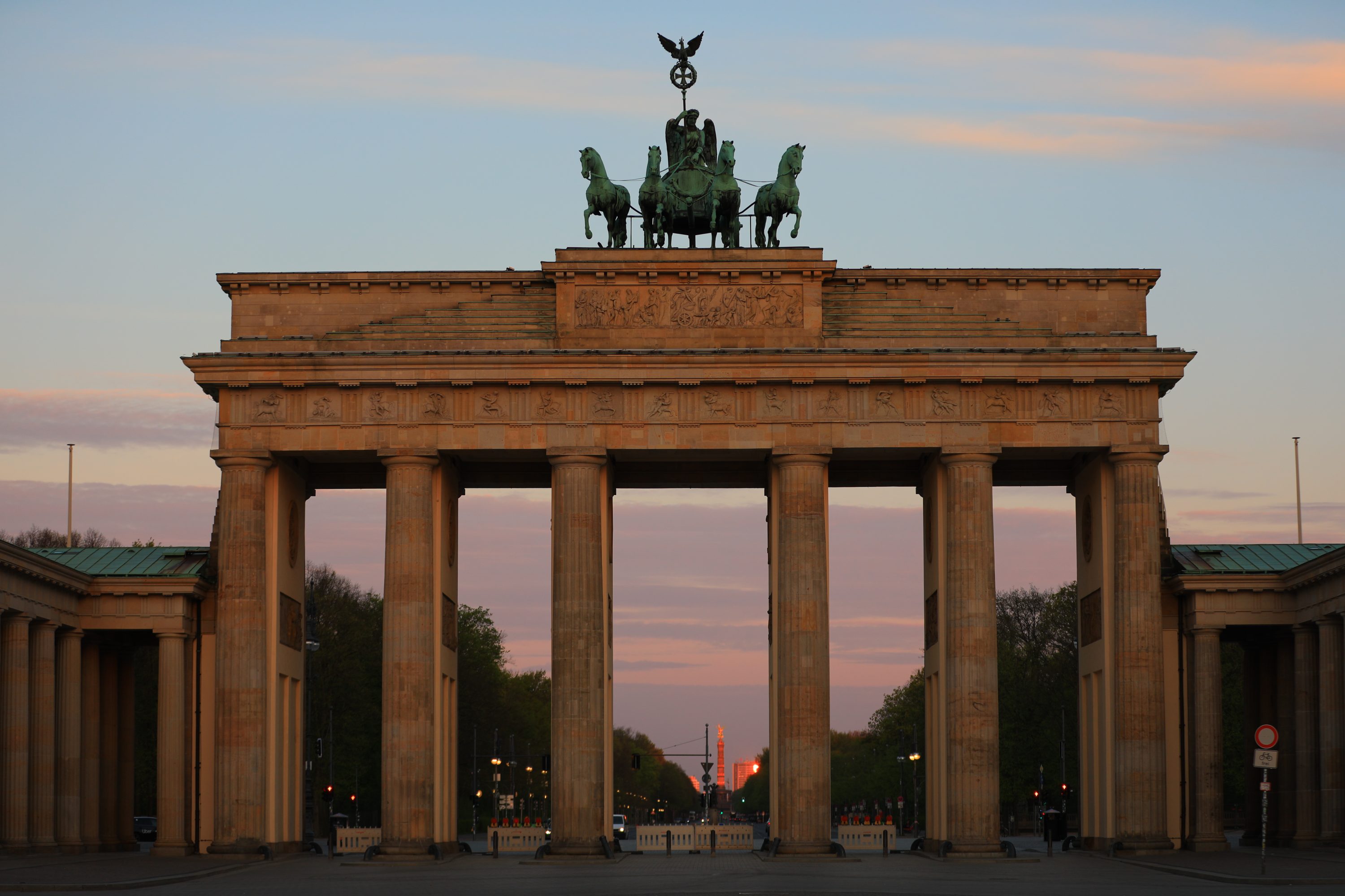 The Brandenburg Gate glowing in the soft golden light of an early Berlin sunrise.
